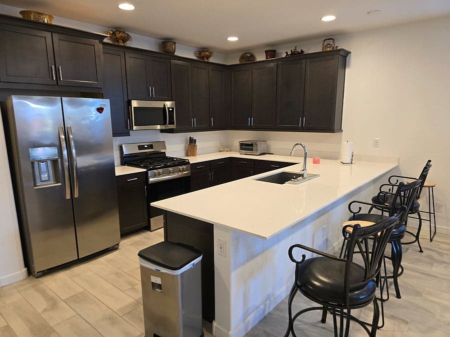 Kitchen with gas range, stainless refrigerator, and breakfast bar seating